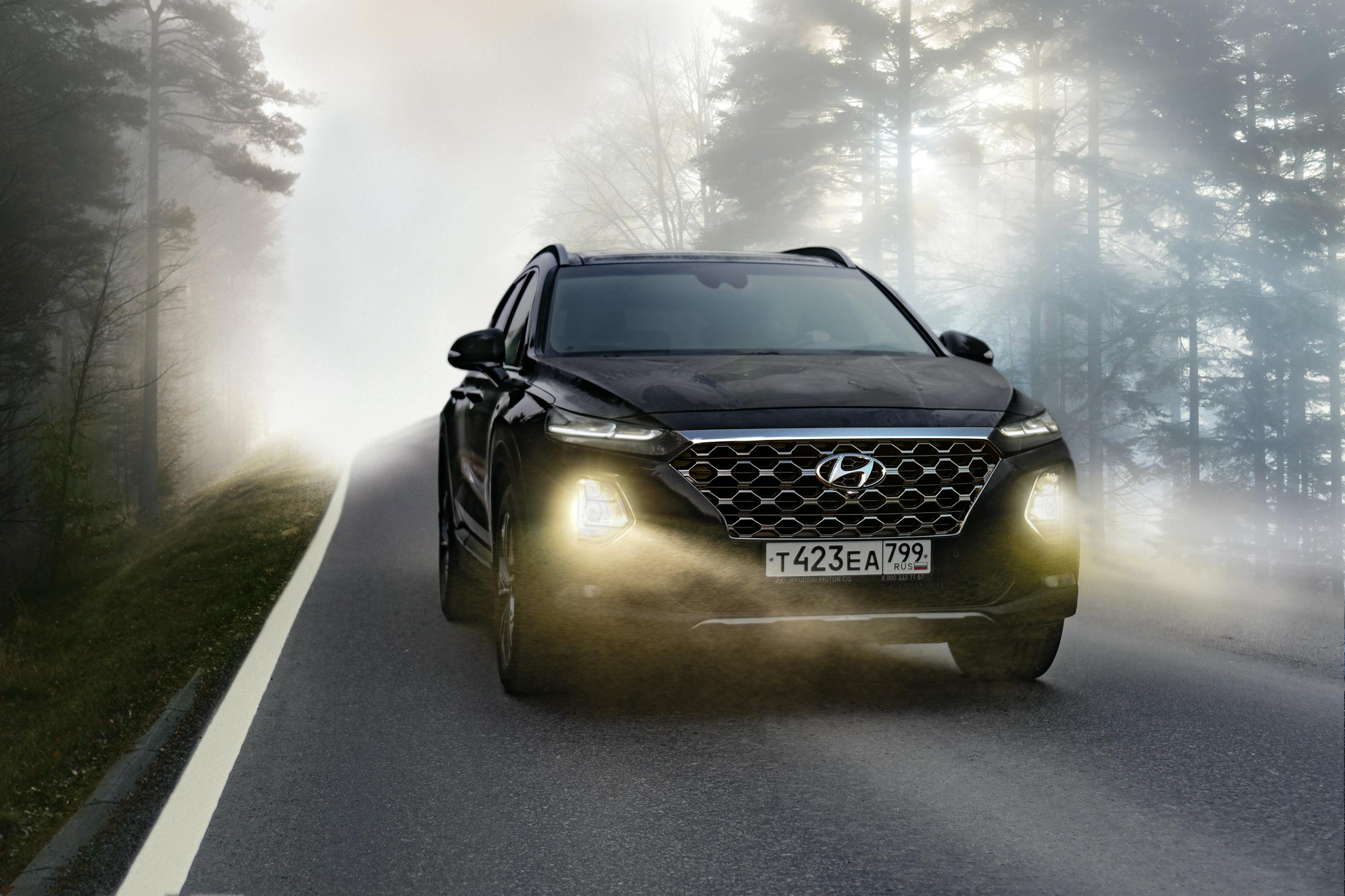 A car driving along a misty road with its headlights on
