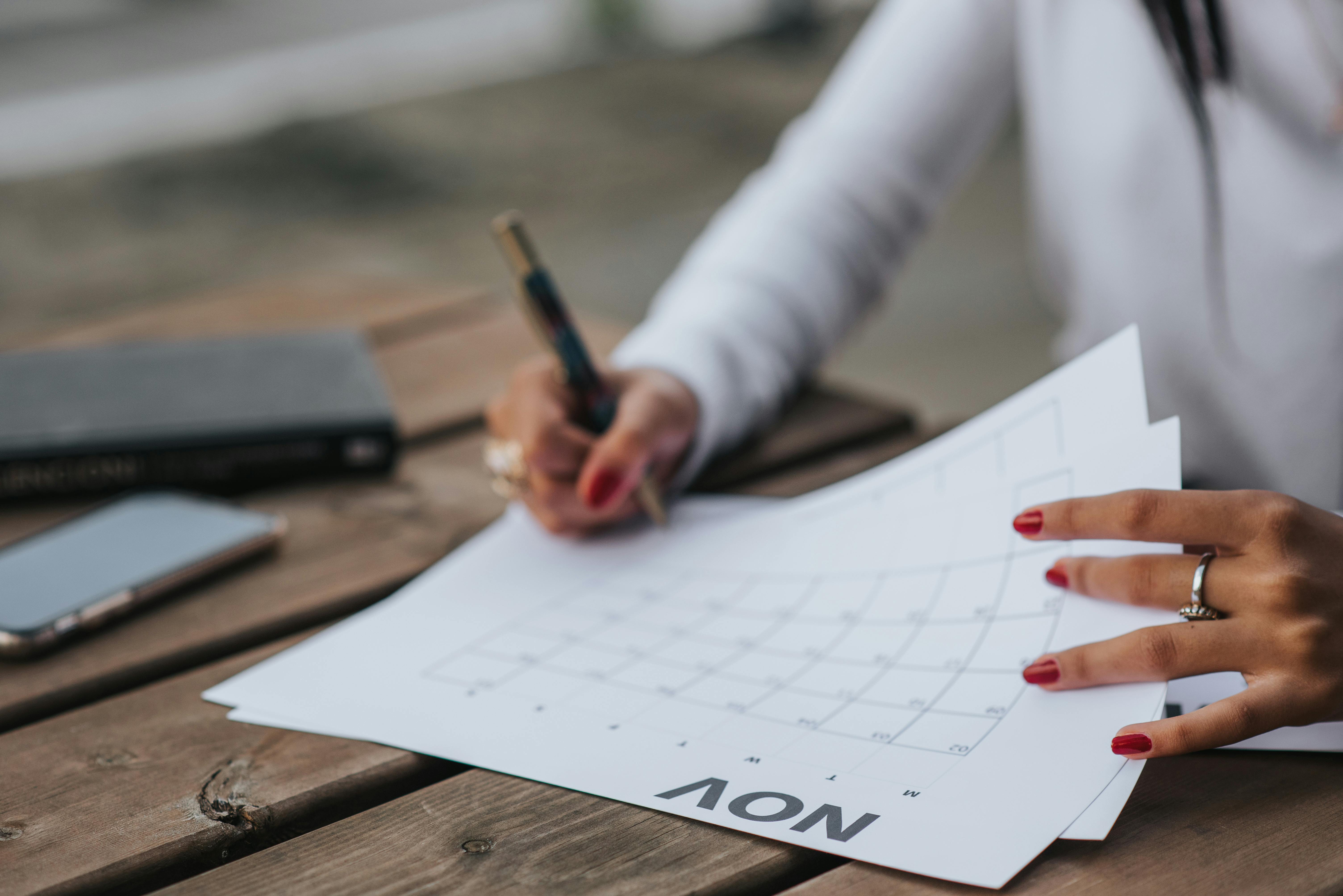 A hand writing on a paper wall calendar