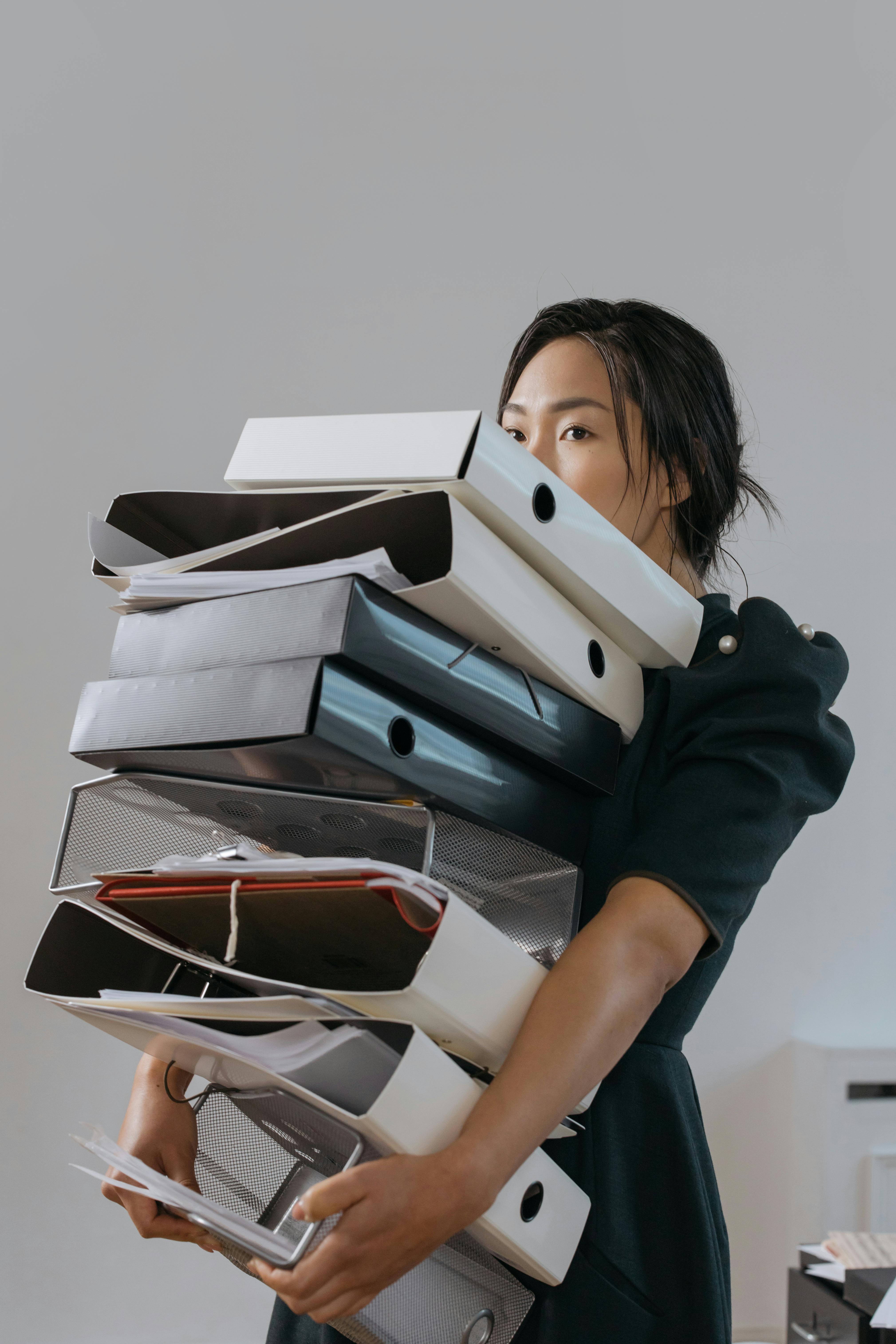 A woman carrying a tall stack of files