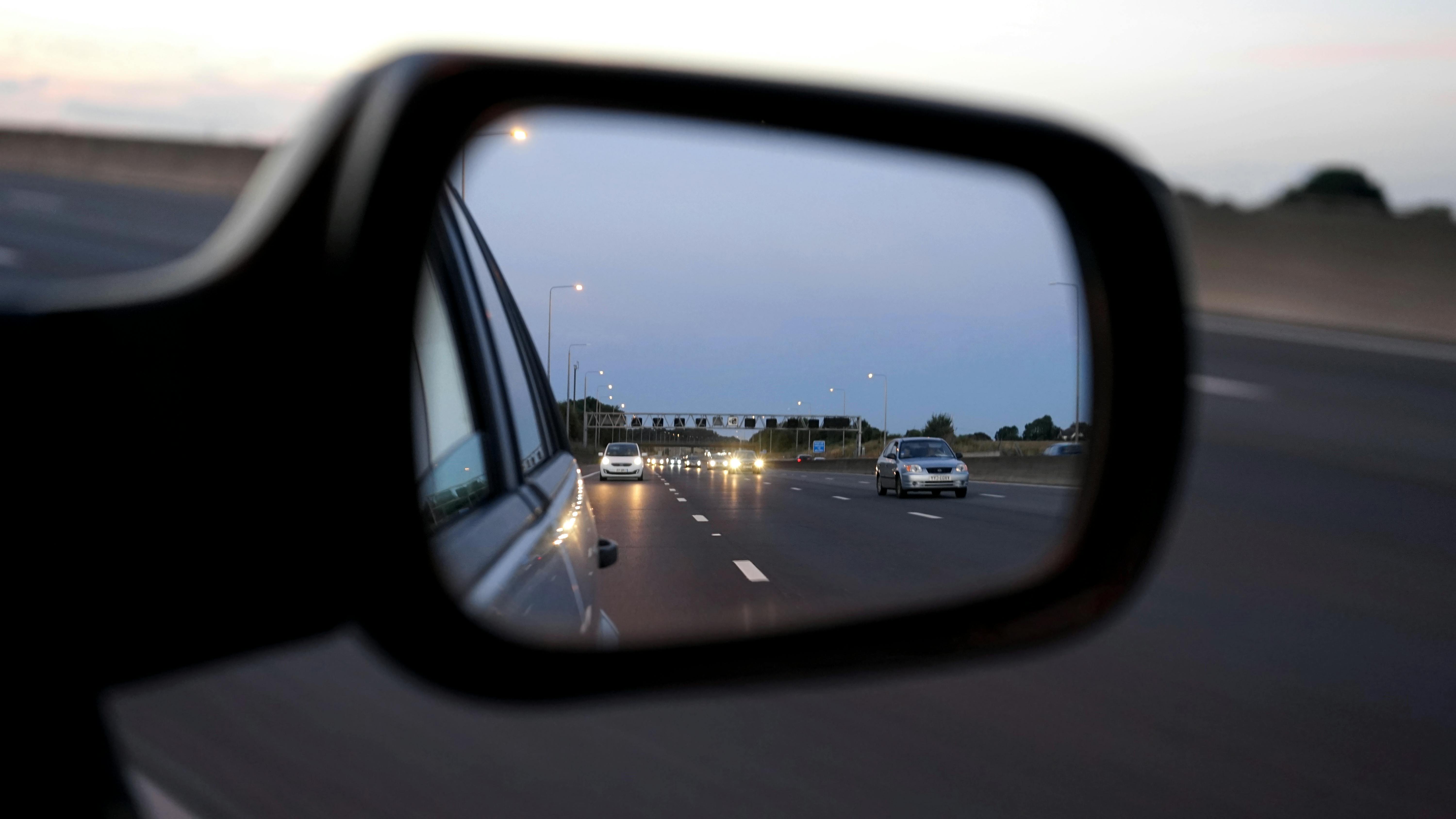 Motorway traffic reflected in a car wing mirror at dusk