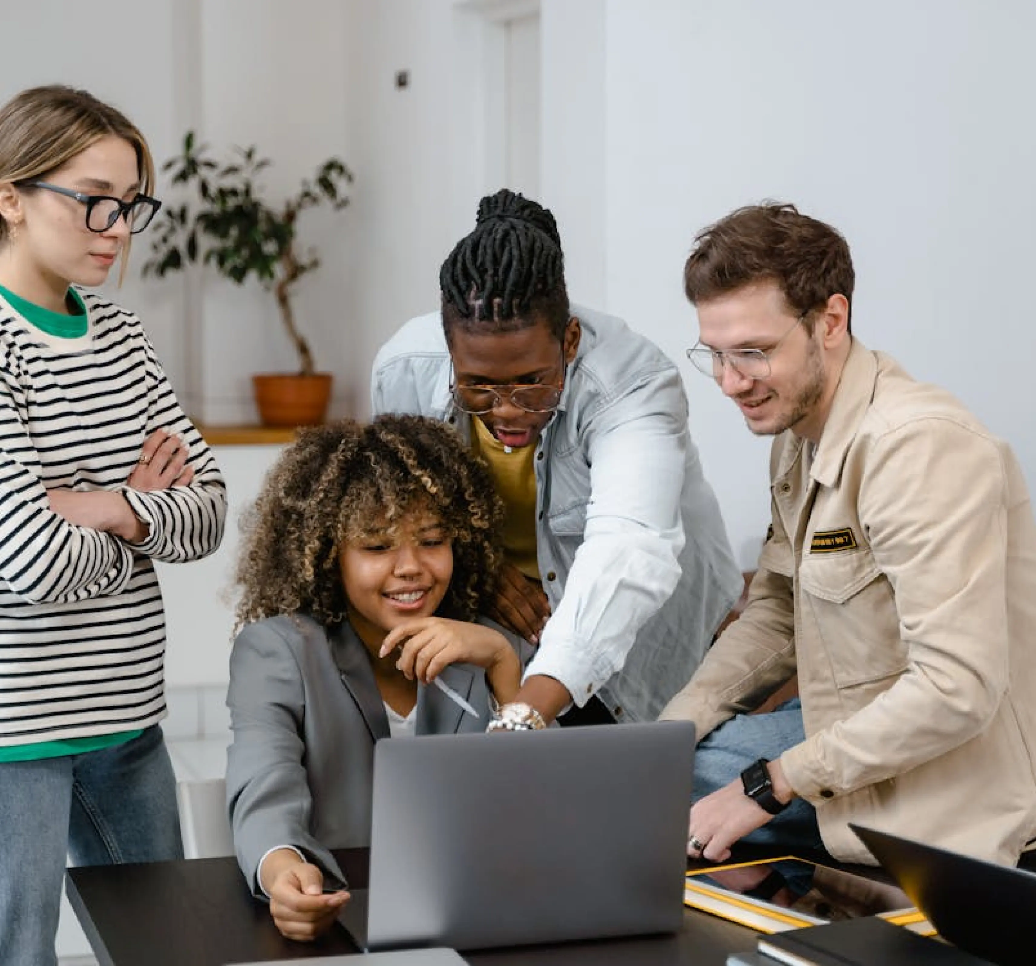 A group of colleagues gathered around a laptop