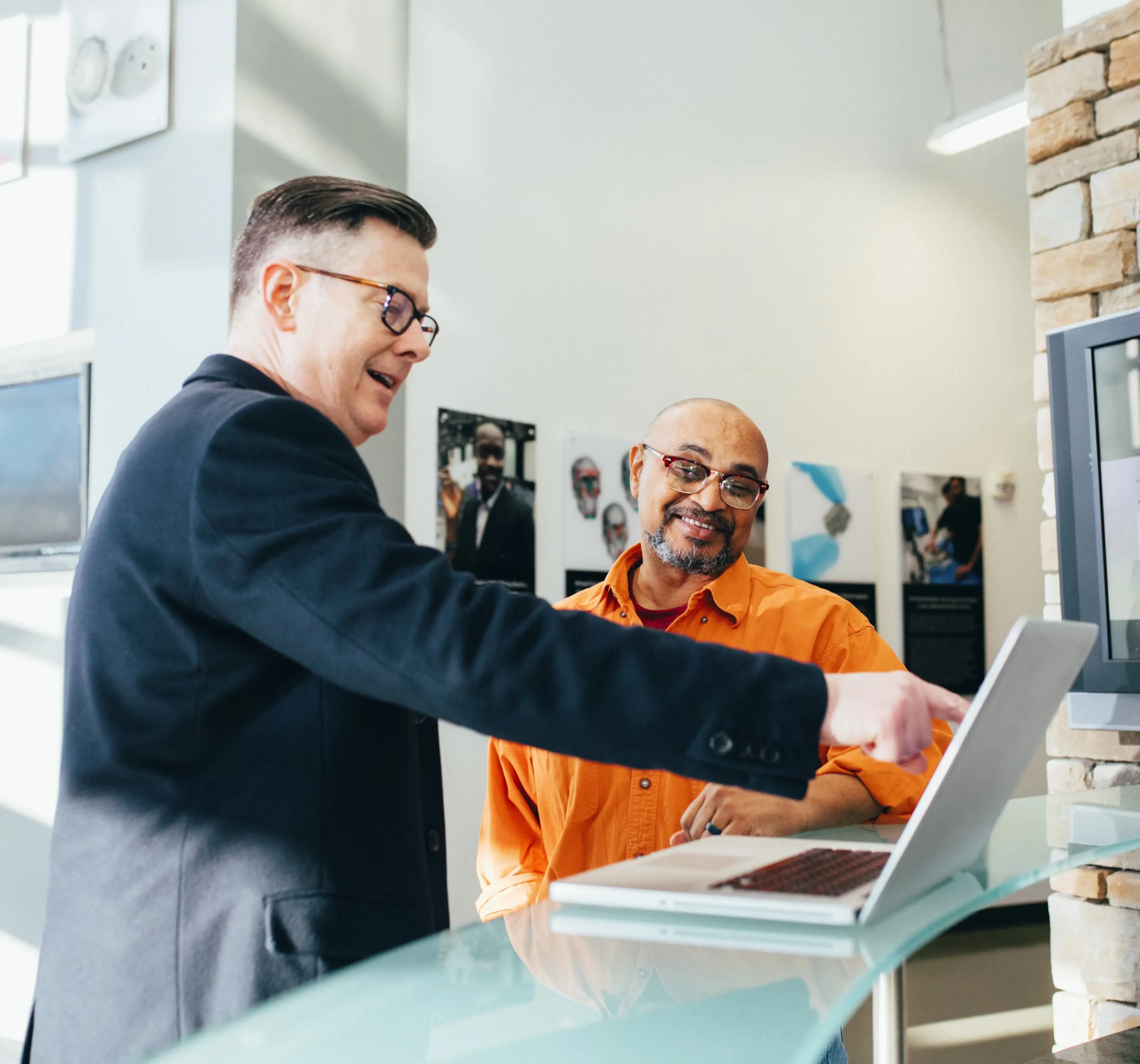 Two men shaking hands across a desk in an office