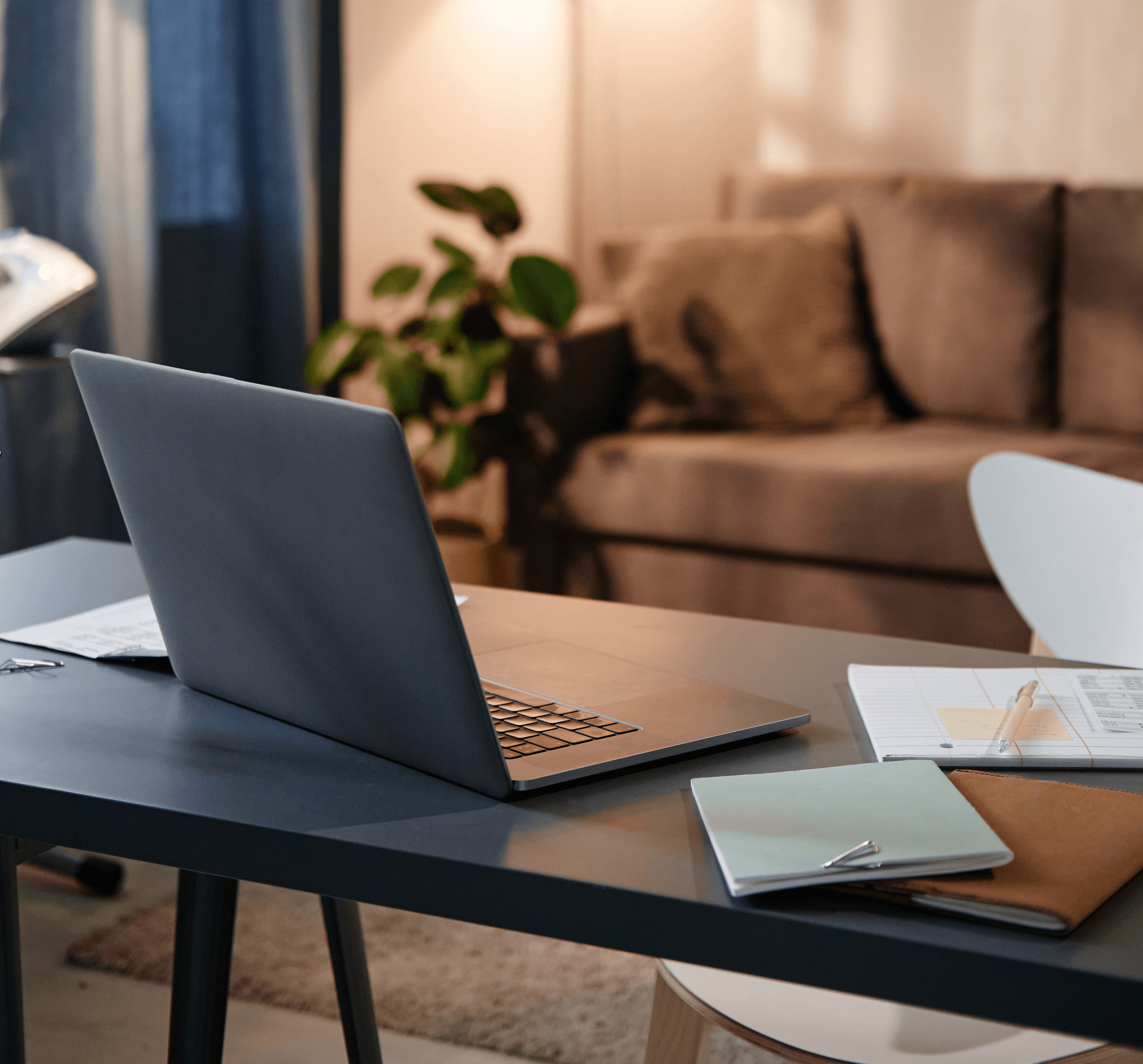 A laptop and notebook set up on a desk at home