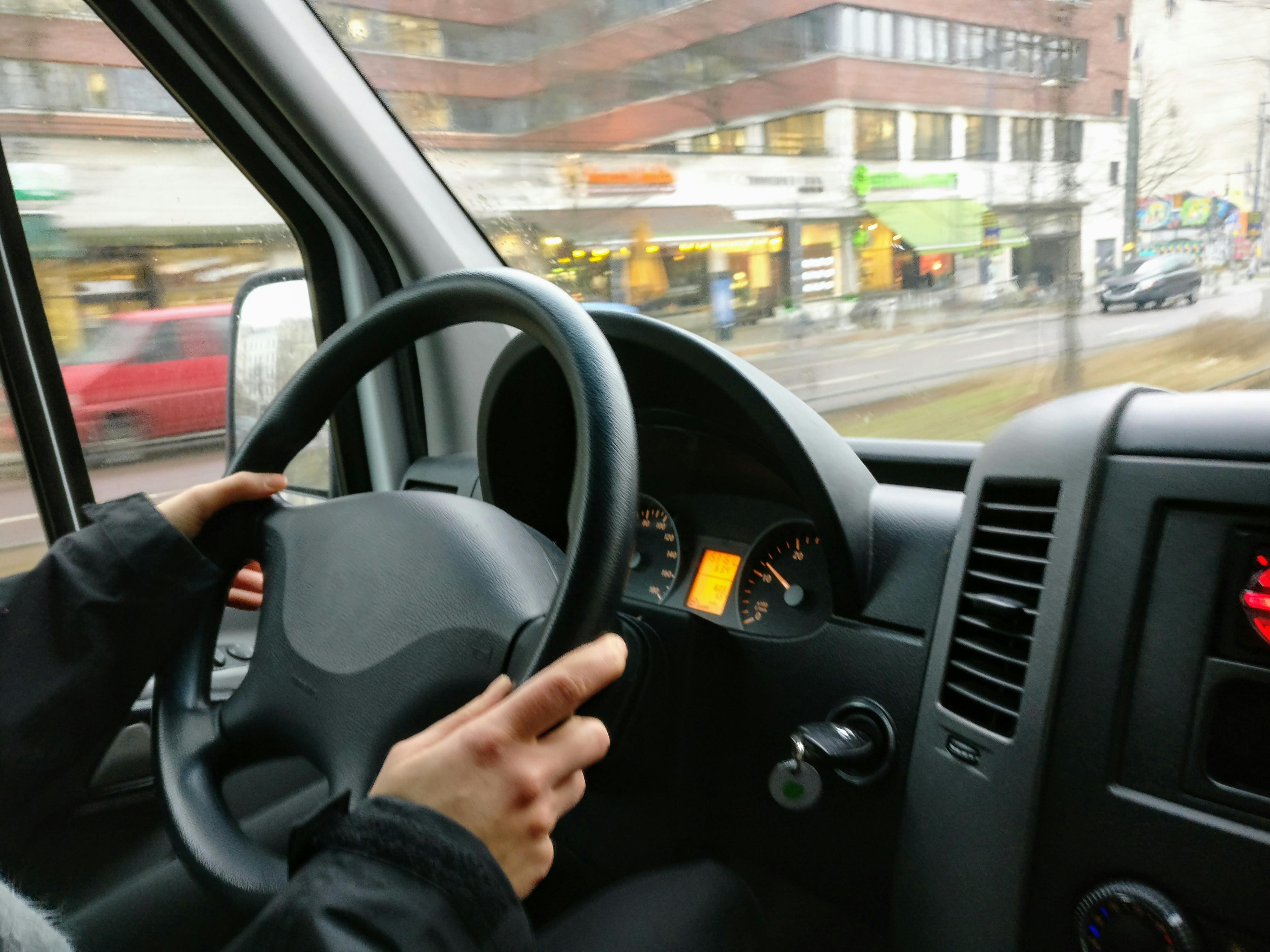 A driver's hands on the steering wheel of a van